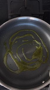 Olive oil swirled in a non-stick pan, heating up on the stove.